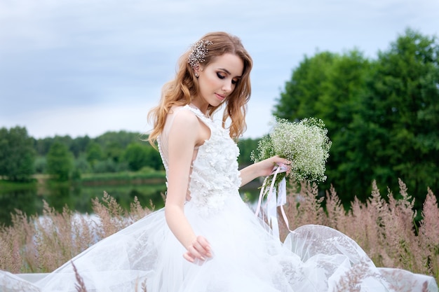 Novia bonita joven en vestido de novia blanco al aire libre