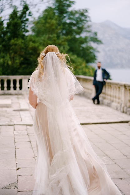 La novia camina a lo largo de la terraza de piedra para el novio con el fondo del mar