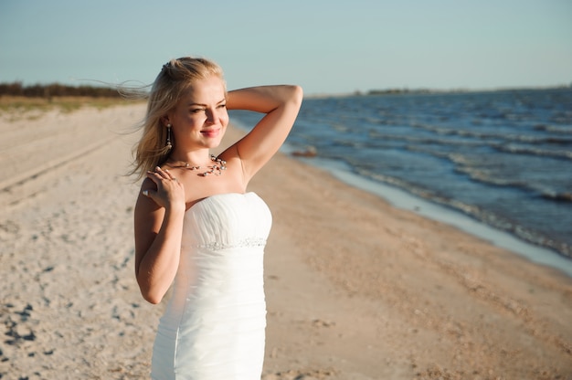 Novia caminando por la costa del mar con un hermoso vestido de novia.