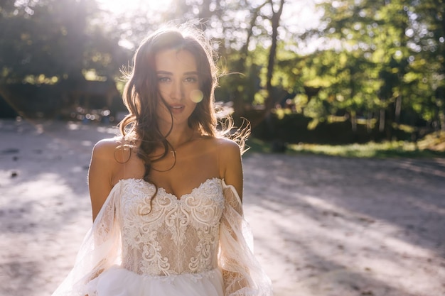 Foto novia caminando en un vestido blanco atractiva dama posando al atardecer