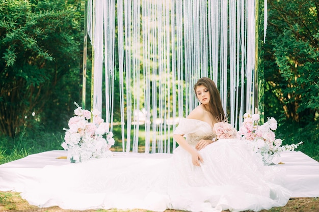 Novia cerca del arco de boda con flores.