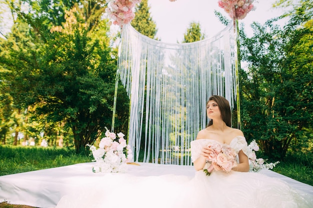 Novia cerca del arco de boda con flores.