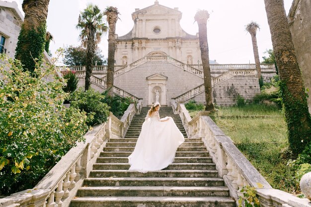 La novia en corona sube las pintorescas escaleras del antiguo templo en prcanj vista posterior