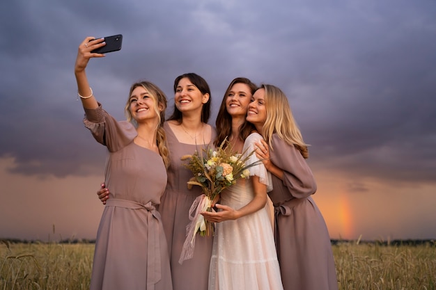 Foto novia y damas de honor tomando selfie tiro medio