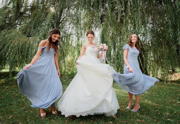 Foto la novia y las damas de honor con vestidos azules giran sobre césped geen