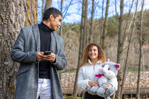 Novia dando un peluche a su novio al aire libre Joven latino recibe un peluche de su novia