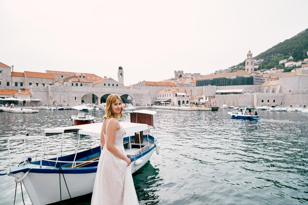 La novia se encuentra mirando hacia atrás al muelle con vistas al antiguo puerto de Dubrovnik, Croacia.