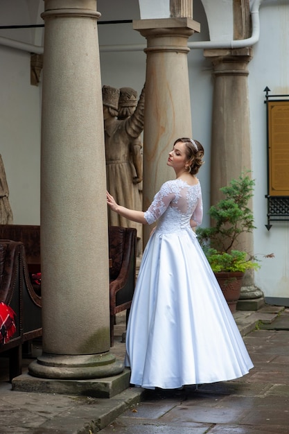 Una novia se encuentra en un patio frente a una columna con estatuas.