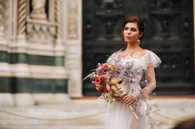 La novia está con un hermoso patrón de flores como una máscara en Florencia, una novia elegante con un vestido de novia