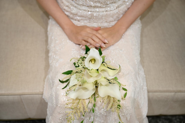 una novia está sentada en un sofá con un ramo de flores