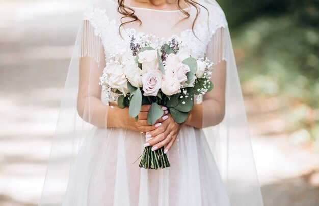 la novia está sosteniendo un ramo de novia. Delicado ramo de novia en tonos blancos y lilas.