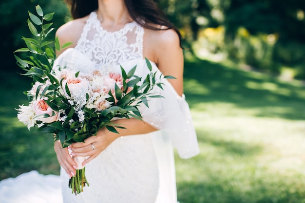 la novia está sosteniendo un ramo de novia. Delicado ramo de novia en tonos blancos y lilas.