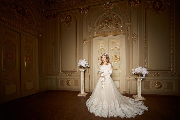 Novia con estilo elegante que mira el interior rico en edificio viejo