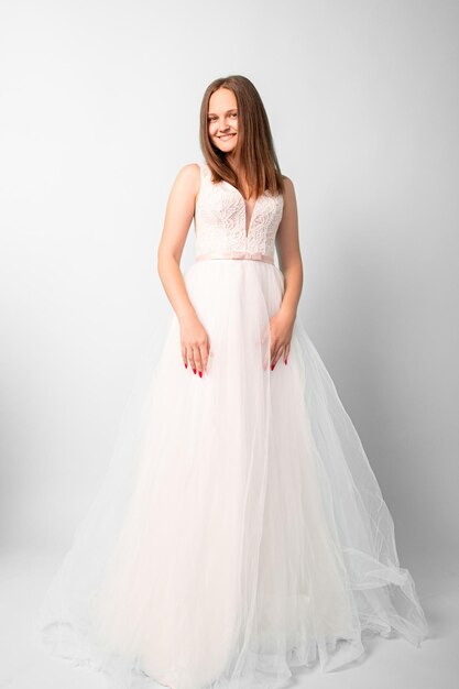 novia feliz Día especial de la boda. Tiro festivo. Mujeres sonrientes con vestido blanco esponjoso posando en cámara en estudio aislado en luz.