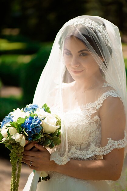 La novia hermosa con la boda florece el ramo, mujer atractiva en vestido de boda.