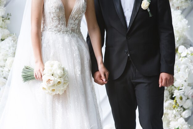 novia con un hermoso ramo y el novio en la ceremonia de la boda. recién casados Feliz recién casados cogidos de la mano de cerca. Día de la boda.