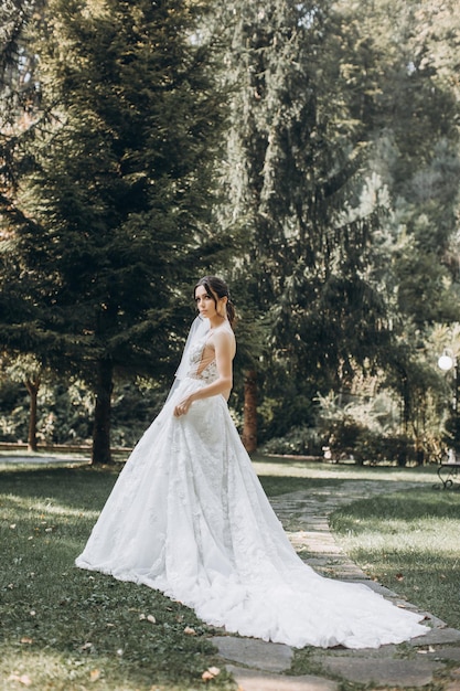 la novia con un hermoso vestido blanco se encuentra en medio de un bosque verde