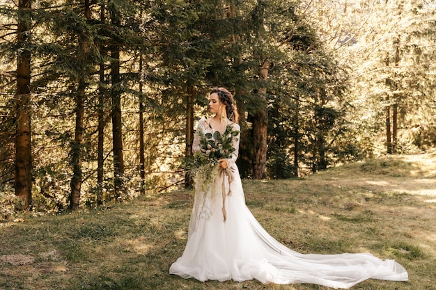 La novia con un hermoso vestido largo blanco, sosteniendo un ramo de novia