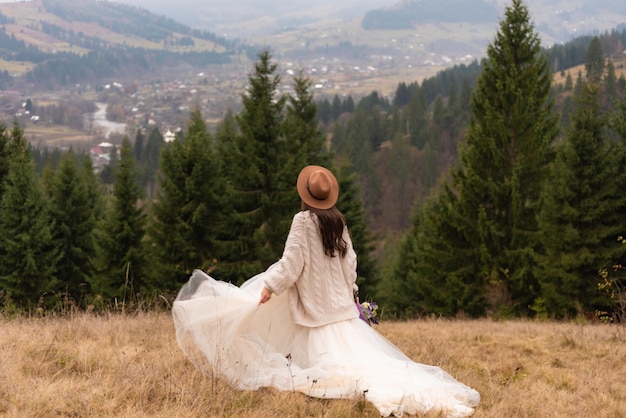 Novia en la imagen de la boda de las montañas. Una hermosa joven con un vestido de novia camina
