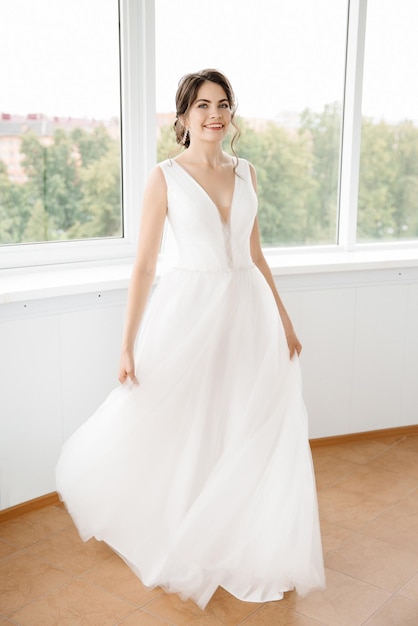 La novia en un interior luminoso gira con un vestido de novia.