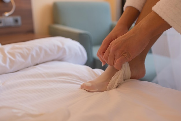 Una novia irreconocible con una bata de seda con hermosas piernas delgadas se está poniendo medias. Preparación de la mañana de la boda. Vestir lencería, boudoir.