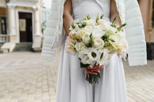 Novia irreconocible en vestido blanco con ramo de cerca