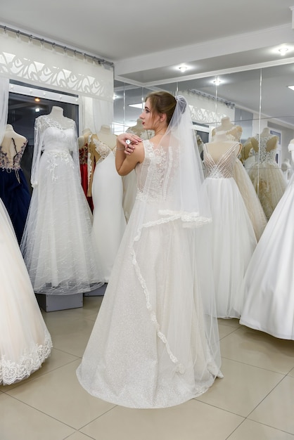 Novia joven y pequeña en vestido de novia en el salón