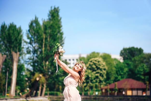 Novia joven con el ramo de la boda al aire libre en el parque