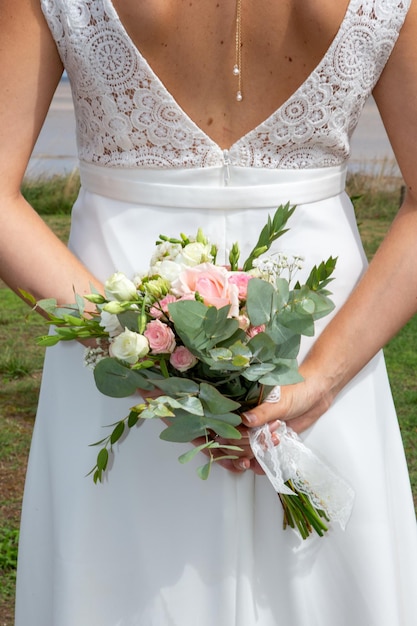 Novia joven con ramo de flores de boda al aire libre en la vista posterior