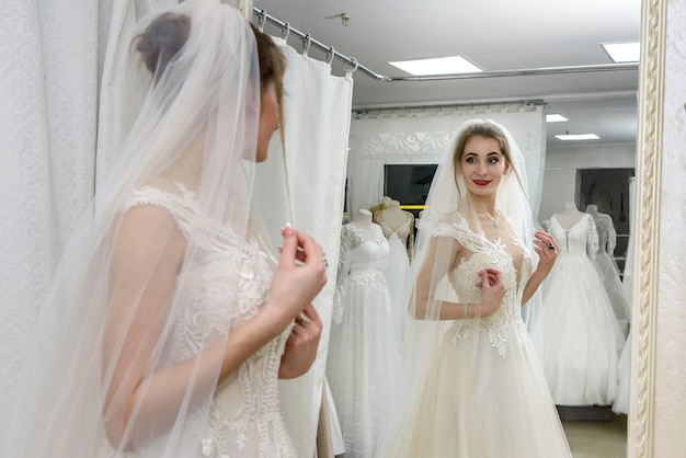 Novia joven en el salón mirando en el espejo en su reflejo