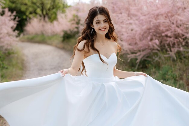 Una novia joven con un vestido blanco está girando en un camino