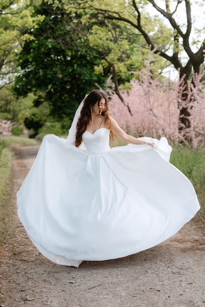 Una novia joven con un vestido blanco está girando en un camino