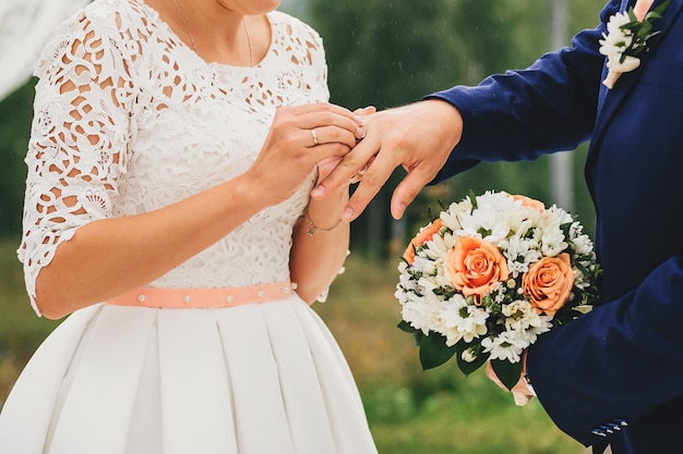 La novia lleva un anillo en el dedo del novio en la boda