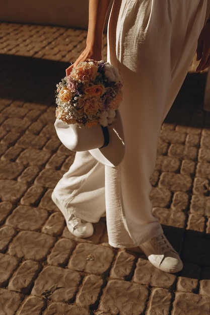 Una novia lleva un ramo de flores en la mano.