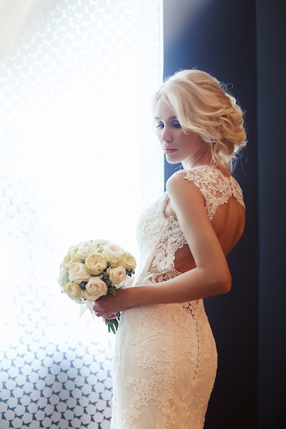 Novia de la mañana Una mujer en un vestido de novia blanco con un ramo de flores