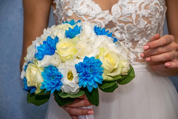 Una novia maravillosa sostiene un ramo de novia en sus manos durante la ceremonia de boda.