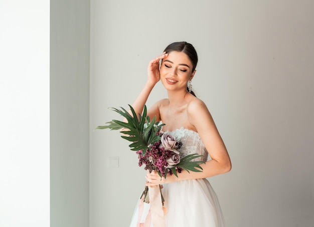 Novia de moda con un vestido largo cerca de la ventana Esperando al novio Interior de la boda Novia de moda de belleza en el hotel Retrato de una novia hermosa Fotografía de boda