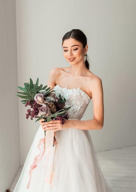 Novia de moda con un vestido largo cerca de la ventana Esperando al novio Interior de la boda Novia de moda de belleza en el hotel Retrato de una novia hermosa Fotografía de boda