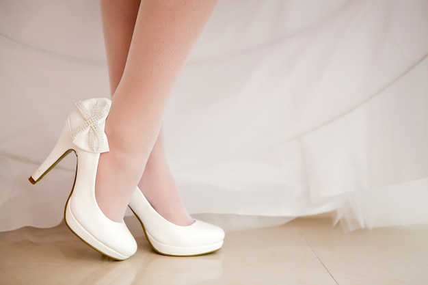 La novia muestra zapatos de boda blancos.