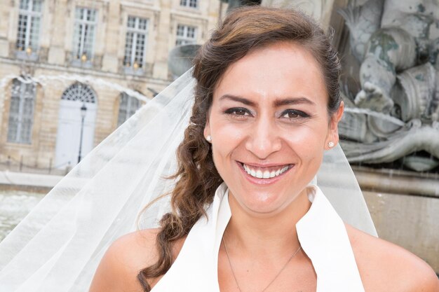 Una novia muy sonriente con un velo en la ciudad