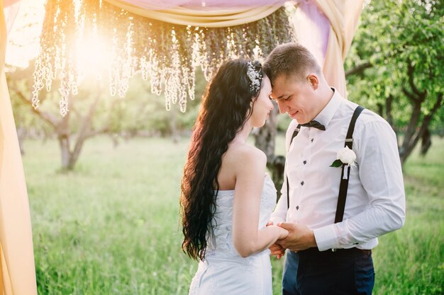 La novia y el novio abrazados bajo los rayos del sol de la tarde Ceremonia de boda