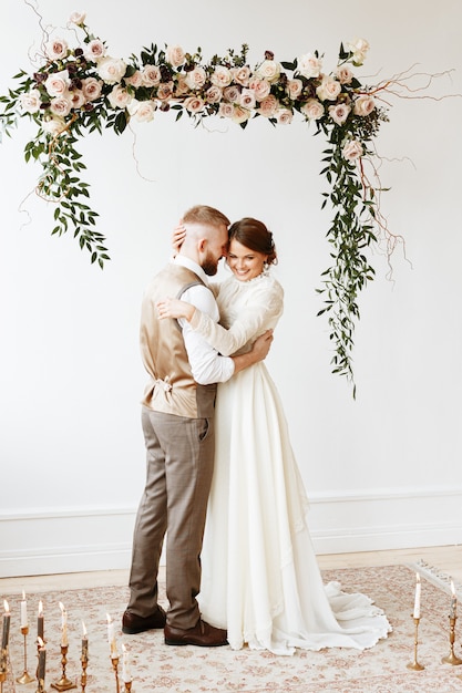 la novia y el novio se abrazan bajo un arco de flores