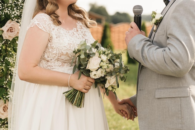 La novia y el novio abrazan las manos de cerca