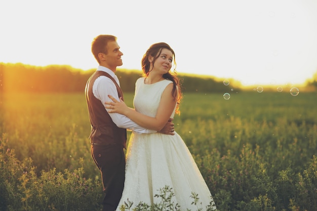 La novia y el novio se abrazan en el parque a la luz del atardecer