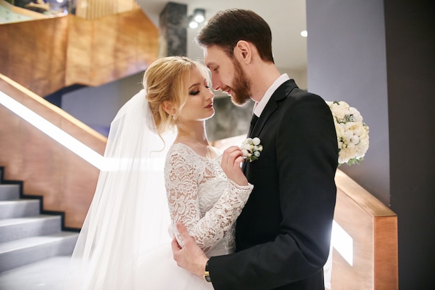 Novia y el novio abrazando y besando mientras está de pie en las escaleras.