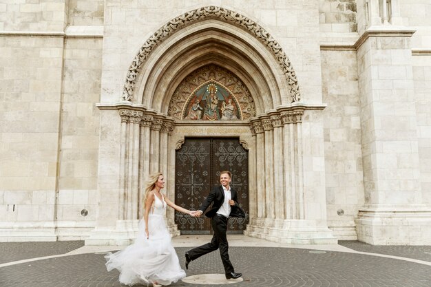 Novia y el novio abrazando en la calle del casco antiguo. Novios enamorados Vestido de diamantes de imitación de lujo.