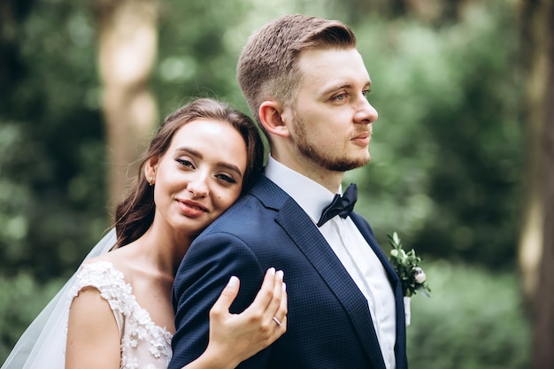 La novia y el novio abrazándose, besándose al aire libre el día de la boda, pareja joven, día de san valentín