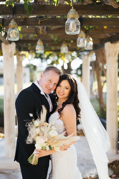 Foto la novia y el novio abrazándose en la pérgola en el jardín