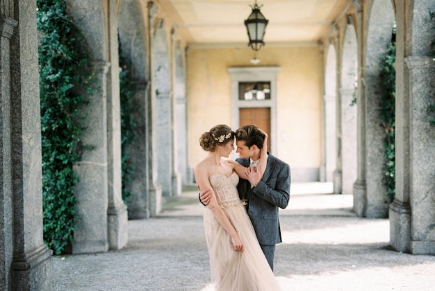 Novia y novio abrazándose en la terraza de una antigua villa lago de como italia