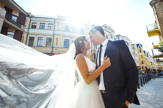 La novia y el novio se besan tiernamente a la sombra de un velo volador Juntos Boda Amor